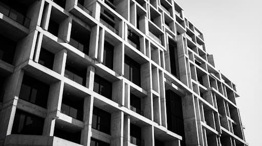 Architectural photograph of a contemporary brutalist concrete facade with clean linear shadows.